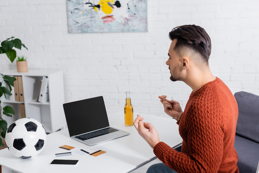 A man doing matched betting at a desk with a laptop and a soccer ball.