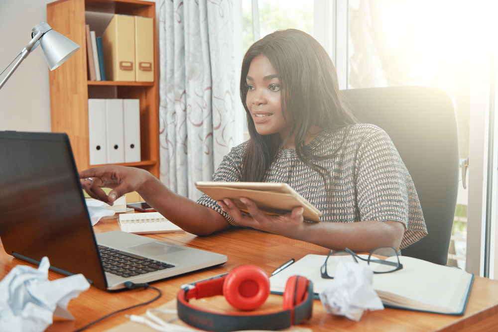 A woman multitasking at a side hustle in the UK with her laptop on a desk.