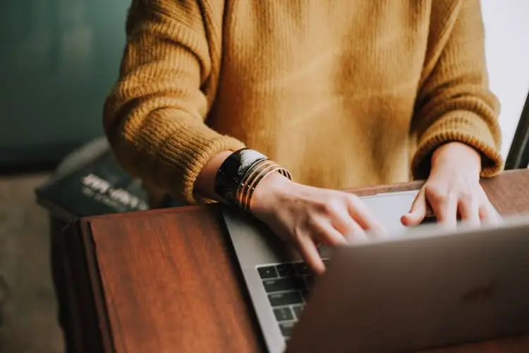 a blogger in brown jumper at work at a laptop