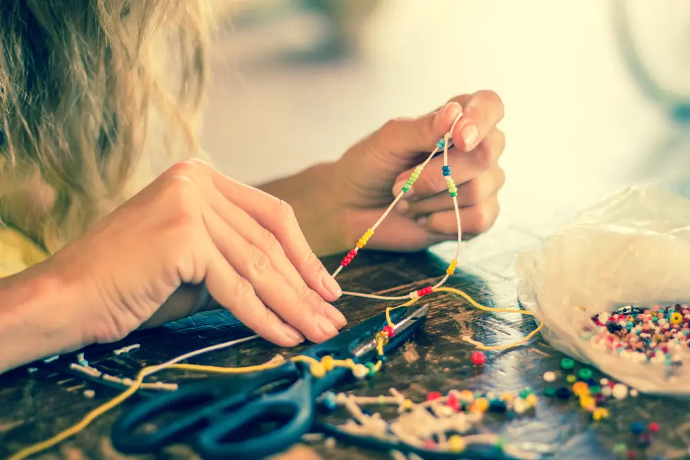 a woman's hands making bead jewellery