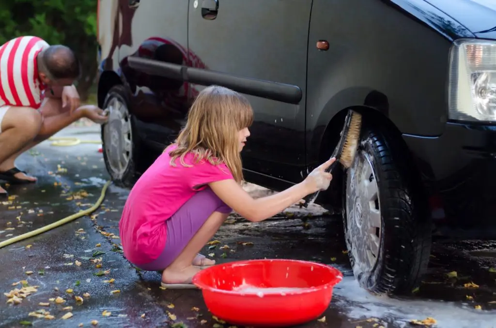 a young girl washing a car for money