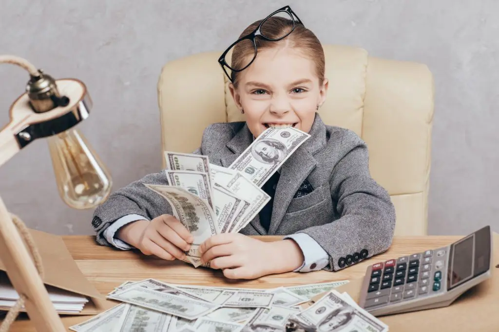 how to make money as a kid - a child dressed as a businessperson with lots of cash