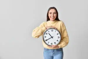 how to make money in one hour featured image: a young woman smiling and holding up a large clock