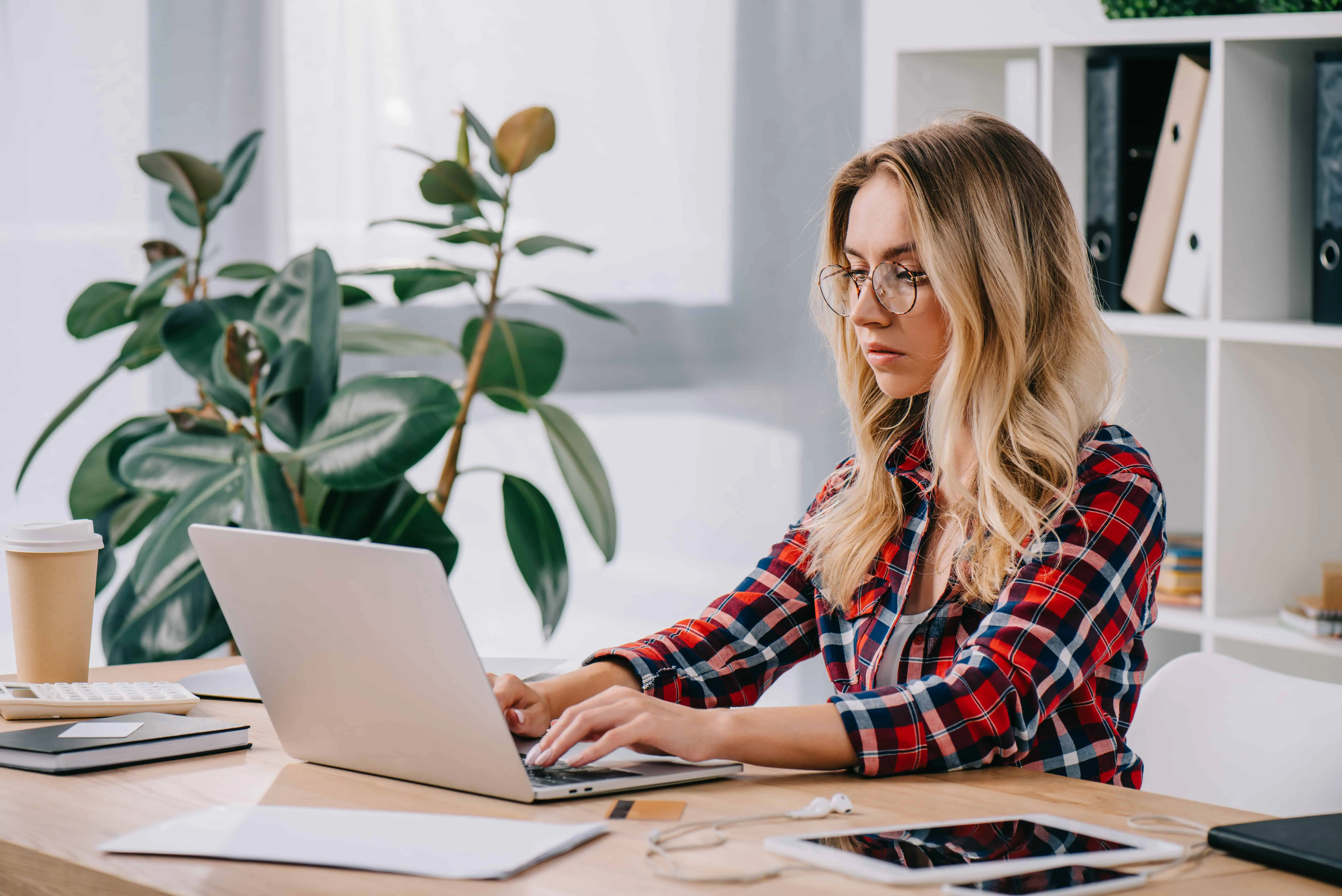 Female blogger working at her desk wearing red shirt