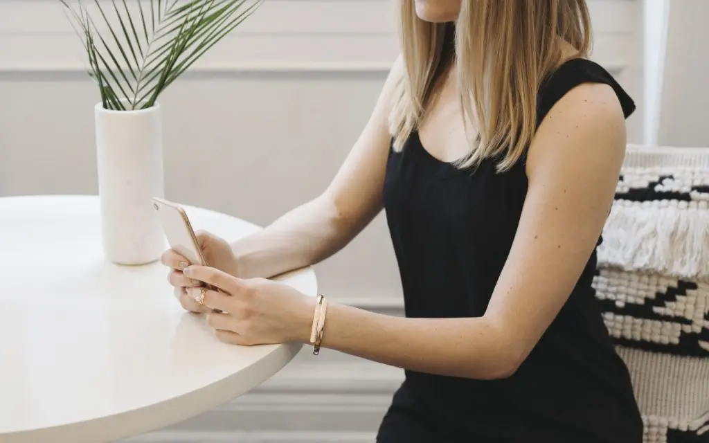 woman in black dress looking at iphone